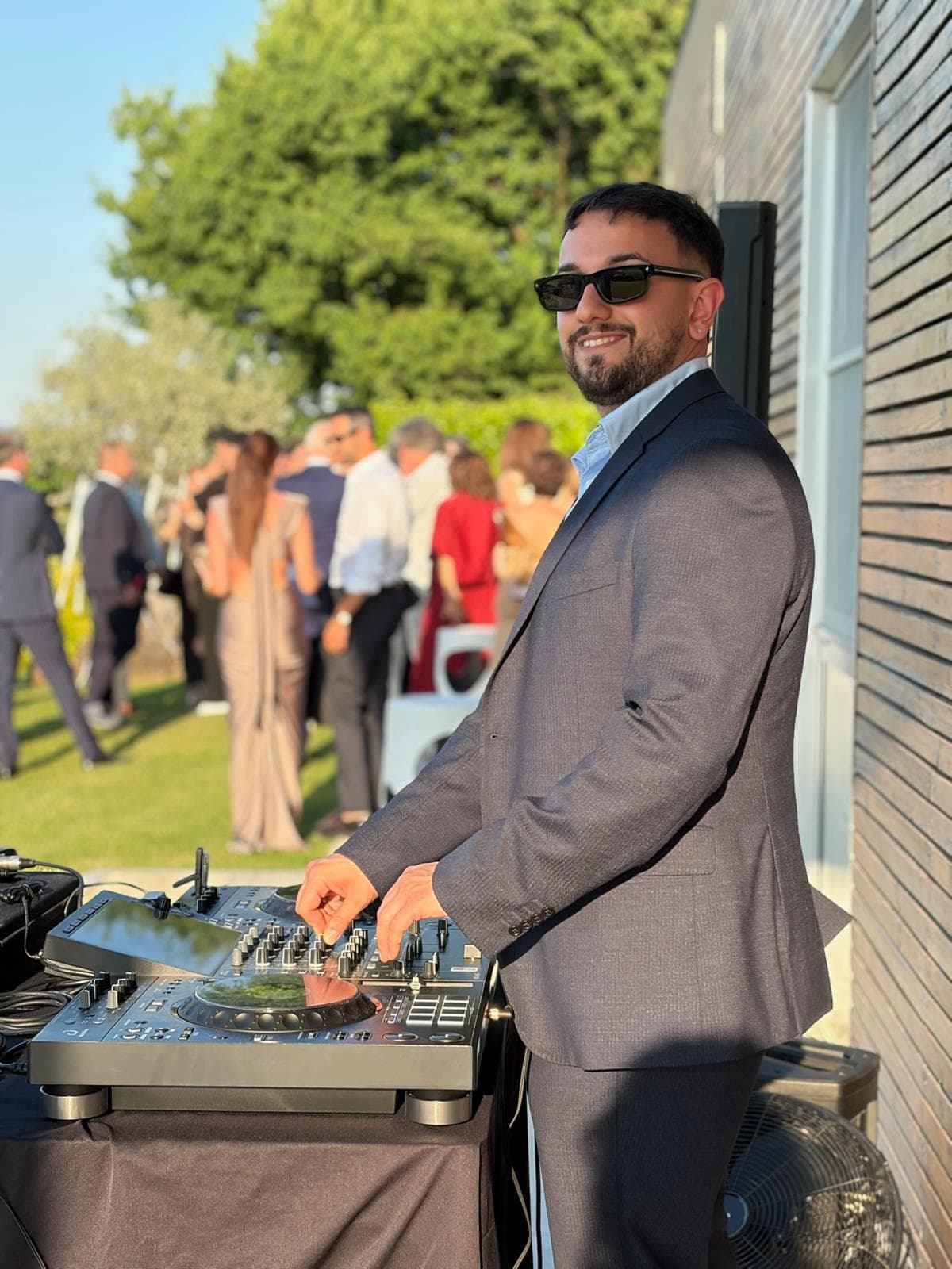 Luca Paone alla console in giacca durante l'aperitivo di un matrimonio in giardino